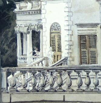 Close-up of a terrace with a white balustrade, two people on the veranda, arms extended to point at the ground.